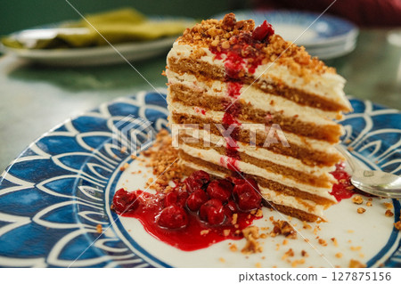 Honey cake with cherries on decorative plate with blue pattern, Tasty dessert  127875156