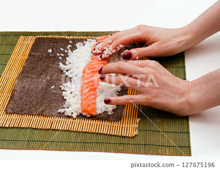 Female hands rolling salmon sushi 127875196
