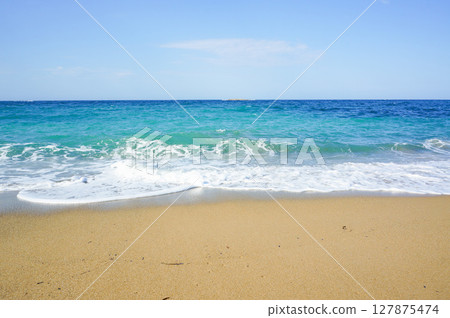 View of waves crashing on a brown sandy beach View of waves crashing on a brown sandy beach 127875474
