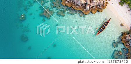 Serene aerial view of a tranquil beach, featuring a boat resting by the crystal-clear blue waters 127875720