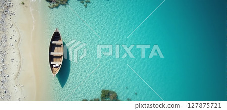 Serene aerial view of a tranquil beach, featuring a boat resting by the crystal-clear blue waters 127875721