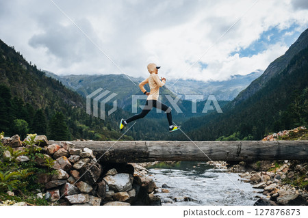 Woman trail runner cross country running in high altitude mountains Woman trail runner cross country running in high altitude mountains 127876873