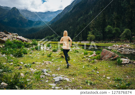 Woman trail runner cross country running in high altitude mountains 127876874