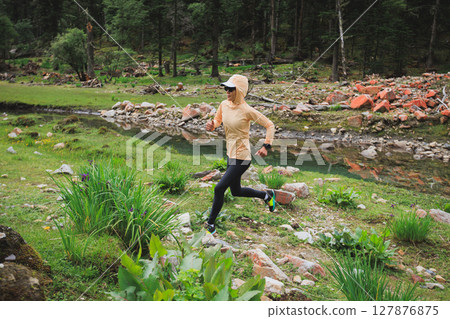 Woman trail runner cross country running in high altitude mountains 127876875