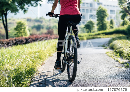 Woman riding mountain biking in sunny park 127876876