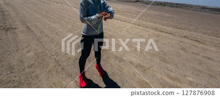 Woman trail runner  set the sports watch cross country running on desert 127876908