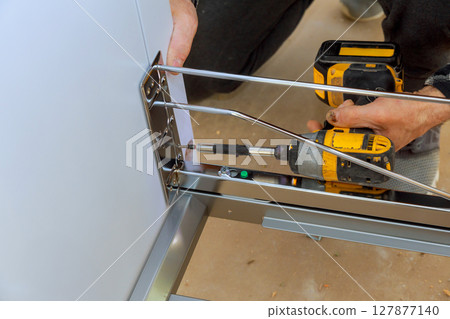 Contractor assembles furniture using cordless drill precise fittings in craftsmanship. Contractor assembles furniture using cordless drill precise fittings in craftsmanship. 127877140