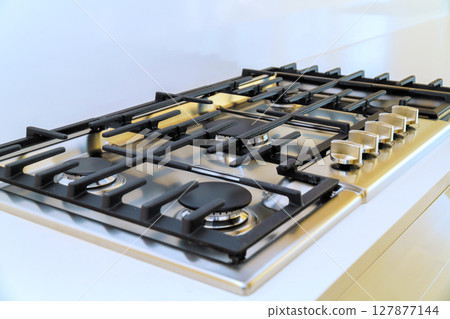 This gas stove features multiple burners, allowing for versatile cooking options in stylish kitchen setting. This gas stove features multiple burners, allowing for versatile cooking options in stylish kitchen setting. 127877144