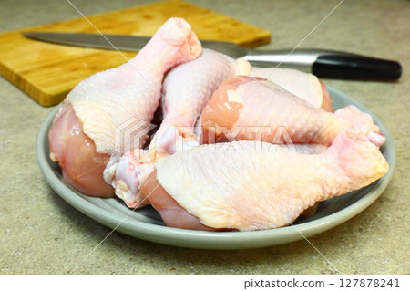 Raw chicken legs with pepper and spices on a board and plate ready for Raw chicken legs with pepper and spices on a board and plate ready for 127878241