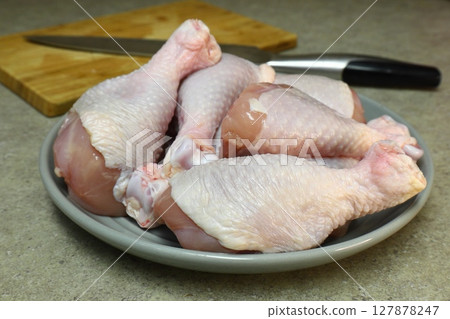 Raw chicken legs with pepper and spices on a board and plate ready for Raw chicken legs with pepper and spices on a board and plate ready for 127878247
