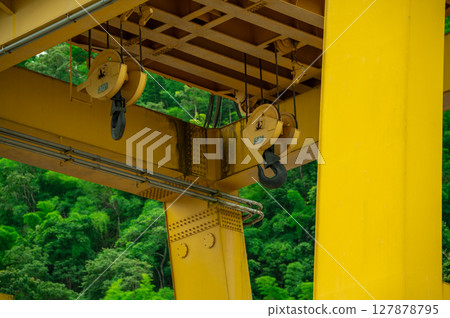 30-ton crane hook installed on hydroelectric dam. Lifting electric equipment, repairing turbines, and managing water flow. Maintenance operations. Construction, engineering, and industrial safety. 127878795