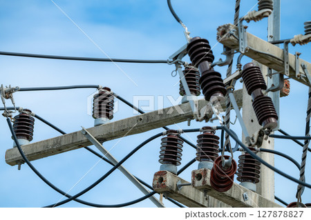 High voltage transmission pole with electrical equipment including cables and insulators on concrete structure under clear blue sky showing modern power grid infrastructure in wind energy facility 127878827