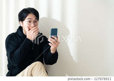 看見智能手機的一個人在牆壁 127878911