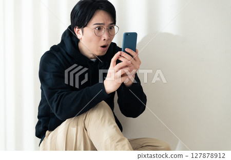 A man seeing a smartphone at the wall A man seeing a smartphone at the wall 127878912