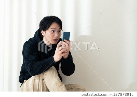 A man seeing a smartphone at the wall 127878913