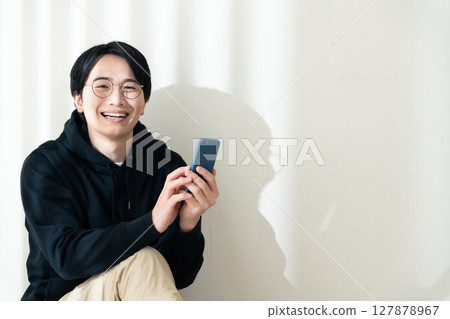 A man seeing a smartphone at the wall A man seeing a smartphone at the wall 127878967