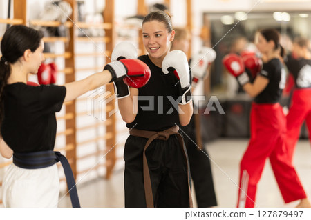 Women fight with hands, using all strength, courage during boxing lesson Women fight with hands, using all strength, courage during boxing lesson 127879497
