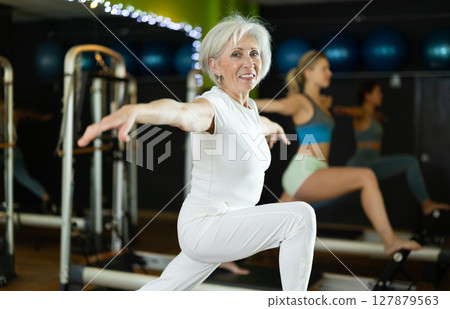 Mature woman actively doing Pilates exercises 127879563