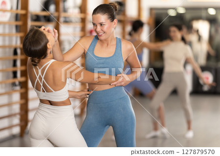 Purposeful engrossed women train during self-defense fight training session in gym Purposeful engrossed women train during self-defense fight training session in gym 127879570