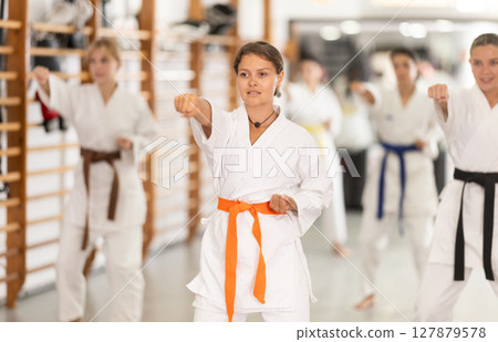 Women students repeat position and perform sequence of punches and painful techniques kata 127879578