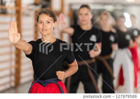 Young woman practicing kata standing in row with others Young woman practicing kata standing in row with others 127879589