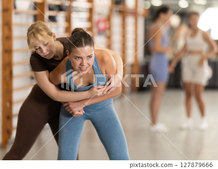 Purposeful engrossed women train during self-defense fight training session in gym 127879666