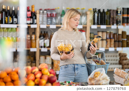 Female shopper chooses between spaghetti and pasta while shopping at supermarket Female shopper chooses between spaghetti and pasta while shopping at supermarket 127879768