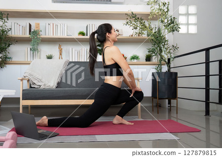 Dynamic Stretching. Woman practicing yoga lunge pose with her corgi dog nearby. 127879815