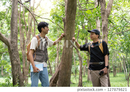 Father and Son Hiking Together. Enjoying nature while exploring a forest. 127879821