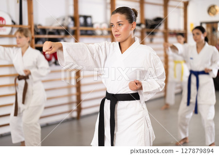 Women students repeat position and perform sequence of punches and painful techniques kata Women students repeat position and perform sequence of punches and painful techniques kata 127879894