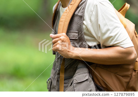 Outdoor Adventure and Eco-Friendly Lifestyle. Individual preparing for a hike with a backpack in nature. Outdoor Adventure and Eco-Friendly Lifestyle. Individual preparing for a hike with a backpack in nature. 127879895