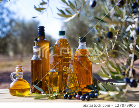 Bottles with olive oil and olive tree on a background of nature Bottles with olive oil and olive tree on a background of nature 127879906