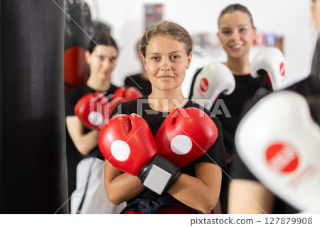 Girl coach in boxing gloves is standing in gym Girl coach in boxing gloves is standing in gym 127879908