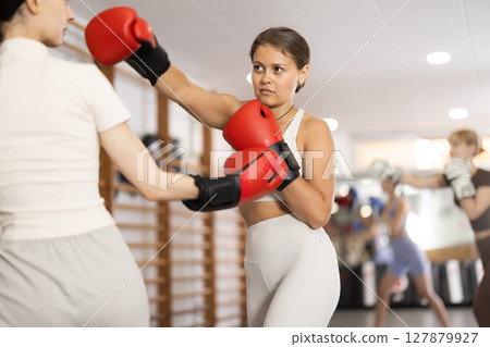 Women fight with hands, using all strength, courage during boxing lesson 127879927