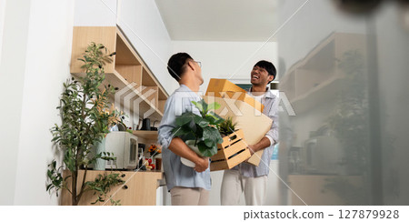 Joyful gay couple unpacking boxes and plants in their new apartment 127879928