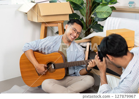 Gay couple enjoying music and laughter while unpacking boxes at home Gay couple enjoying music and laughter while unpacking boxes at home 127879967