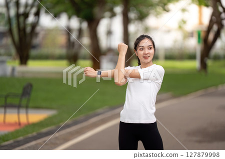 Fitness and Exercise. Woman warming up by stretching her arms in a park. 127879998