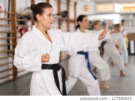 Women practice fighting stances during karate 127880025