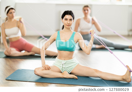 Young girl doing arm workout with band sitting leg extended 127880029