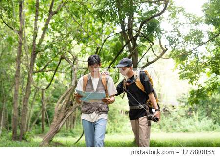 Father and Son Hiking Journey. Navigating through the forest with a map. Father and Son Hiking Journey. Navigating through the forest with a map. 127880035