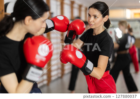Young girl training boxing with partner during sports classes Young girl training boxing with partner during sports classes 127880037