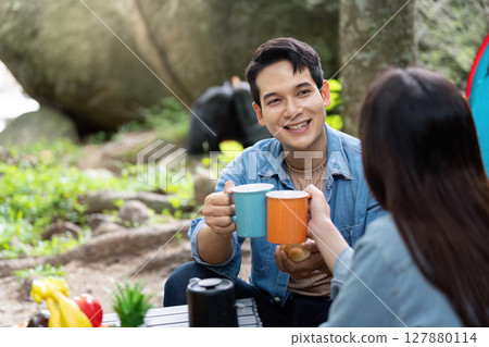 Joyful Couple Camping and Toasting with Coffee Mugs 127880114