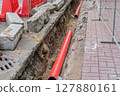 Road repairs, pipe, pile of sand. Red and white plastic barriers blocking the road. 127880161