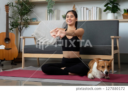 Yoga and Companionship. Young woman meditating with her dog in a peaceful home setting. Yoga and Companionship. Young woman meditating with her dog in a peaceful home setting. 127880172