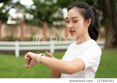 Fitness and Wellness. Young woman checking smartwatch while preparing for outdoor exercise. 127880201