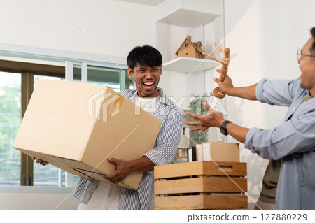 Playful gay couple enjoying unpacking boxes in their shared space Playful gay couple enjoying unpacking boxes in their shared space 127880229