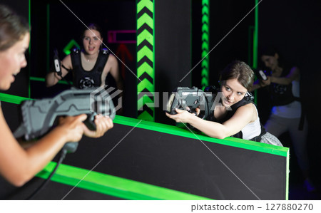 Portrait of excited girlfriends playing enthusiastically laser tag game two teams opposite each other in room Portrait of excited girlfriends playing enthusiastically laser tag game two teams opposite each other in room 127880270