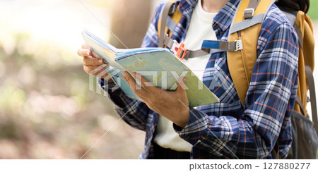 Nature Exploration. Hiker reading map while standing outdoors. Nature Exploration. Hiker reading map while standing outdoors. 127880277