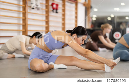 Young girl doing leg stretching in group Young girl doing leg stretching in group 127880293