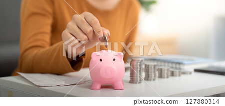 Savings and Financial Responsibility. Woman depositing coins into a piggy bank. Savings and Financial Responsibility. Woman depositing coins into a piggy bank. 127880314